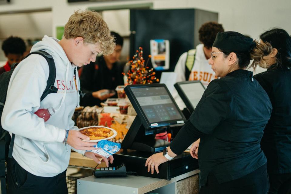 student with food in hand  entering his pin during lunch checkout