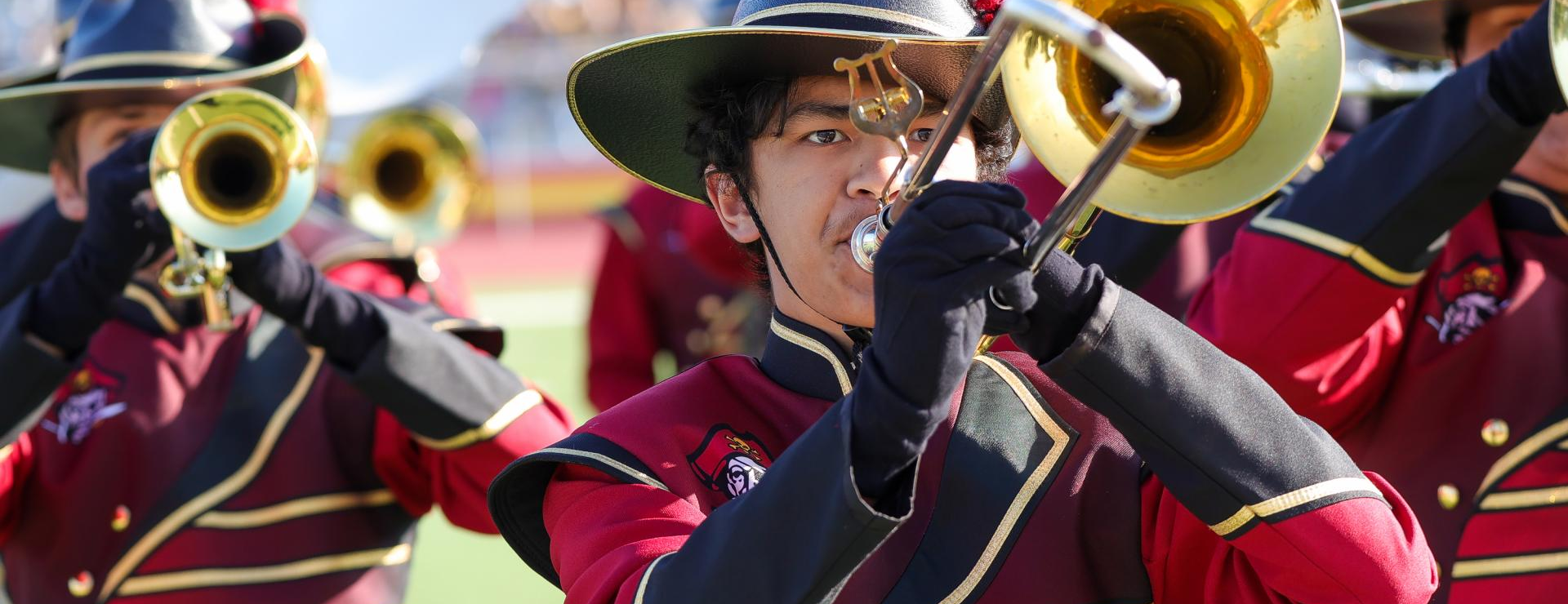 Image of trombone player in full uniform on the football field.