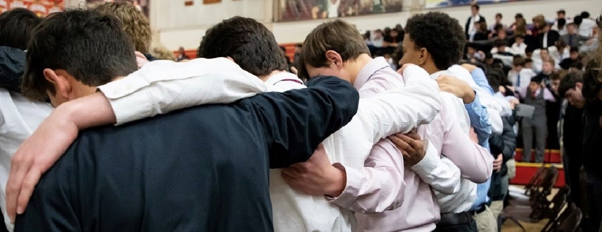 boys at Mass with hands over shoulders praying