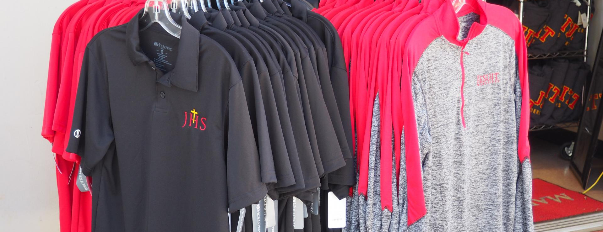 Clothing rack showing long and short sleeved shirts with Jesuit Logo