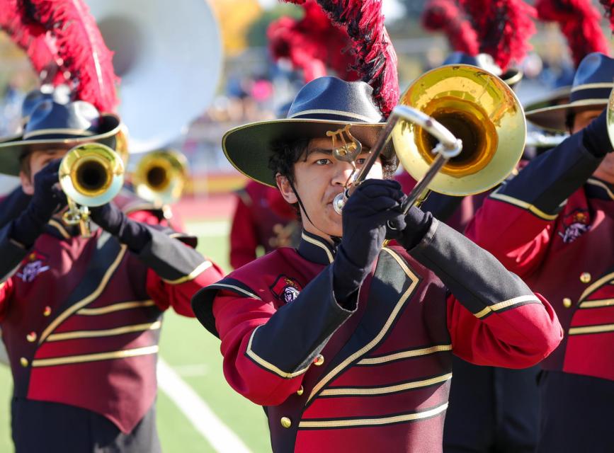 Image of trombone player in full uniform on the football field.