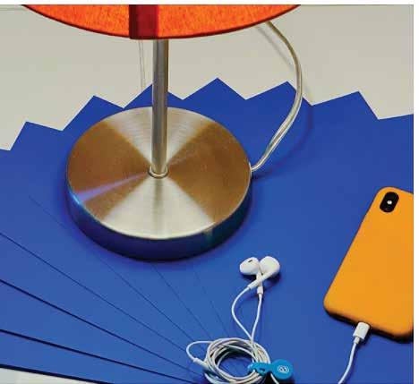 Bright orange lamp on a desk with a yellow phone on blue papers