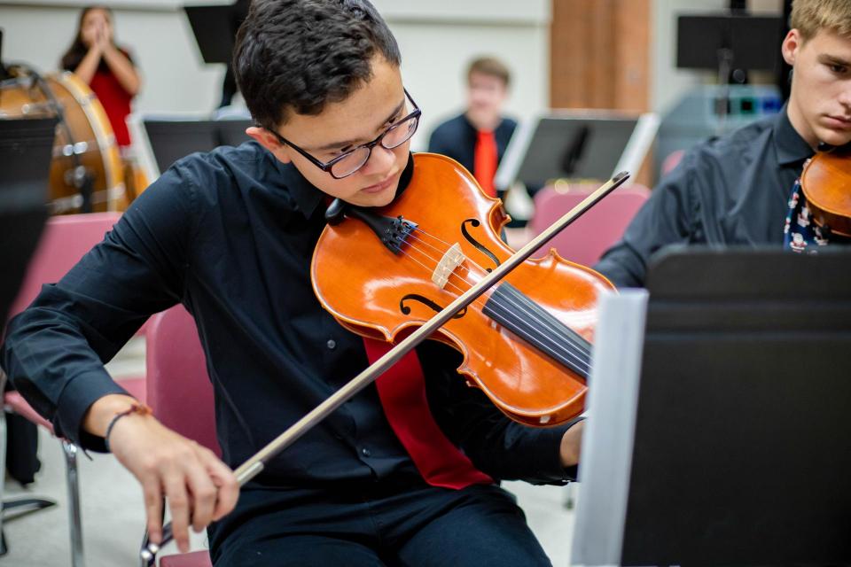 Student in black shirt and tie playing violin