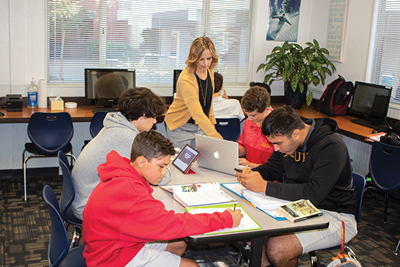 Image of ASC director assisting a group of students at a table.