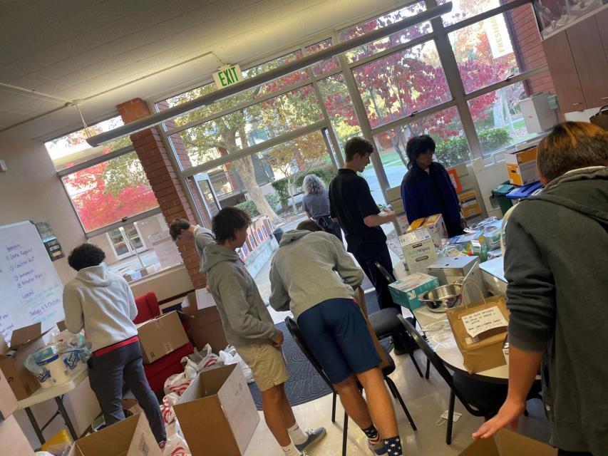 Students around tables with boxes, sorting