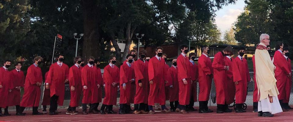 Rev. McGarry, SJ walks along side a line of graduates preparing for procession