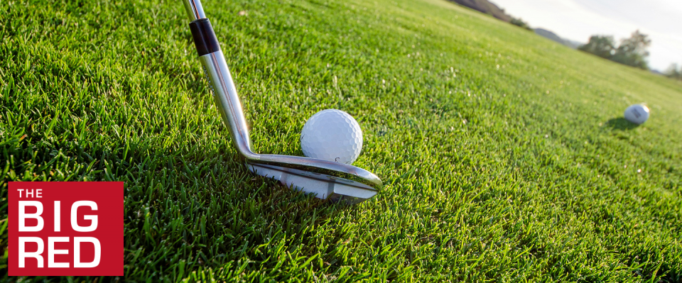 closeup of club hitting ball on green