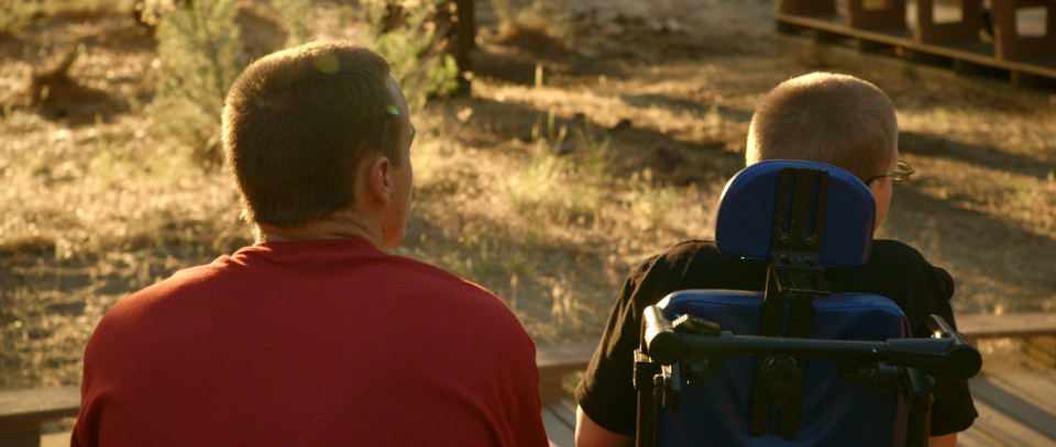 On a late summer afternoon counselor and camper sitting side by side looking away from camper