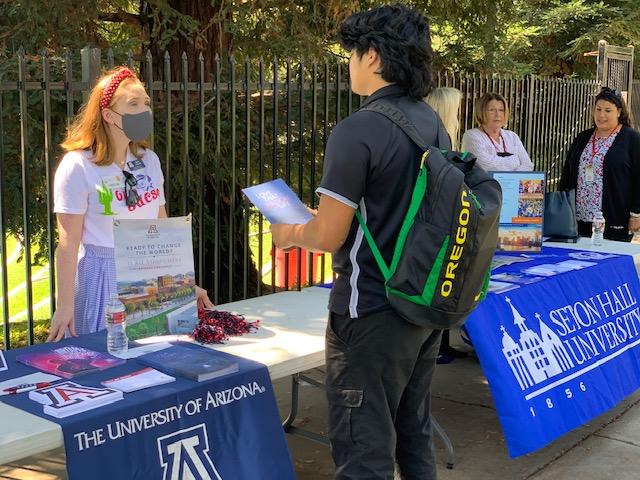 Student asks questions at college booth on campus