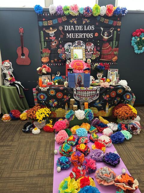 a table covered in colorful fabric, paper flowers, real flowers and photos