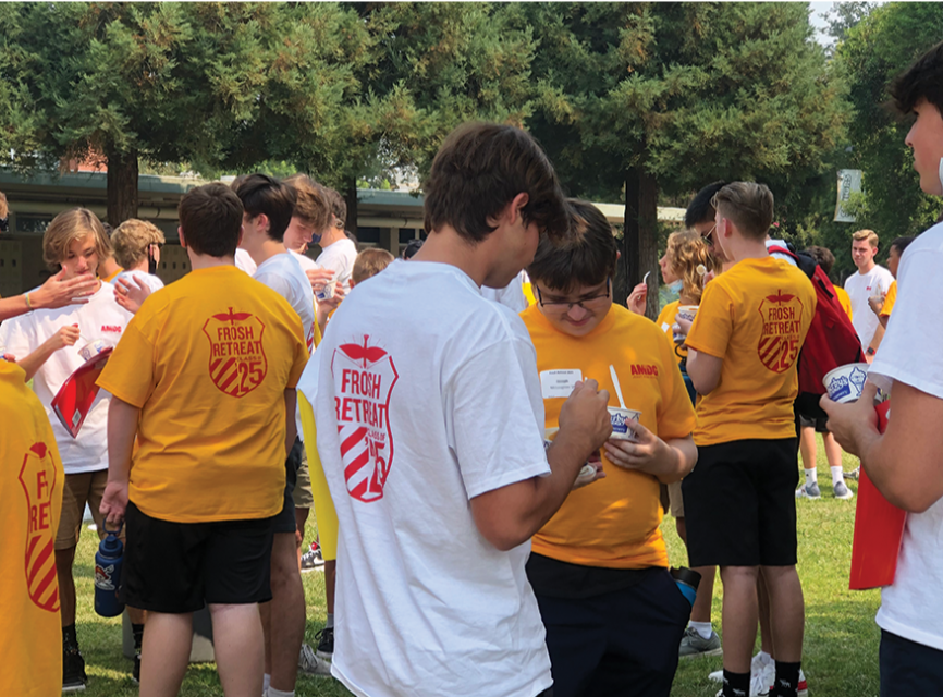 Image of the 2021 Retreat showing smiling freshman and seniors eating icecream together on grass
