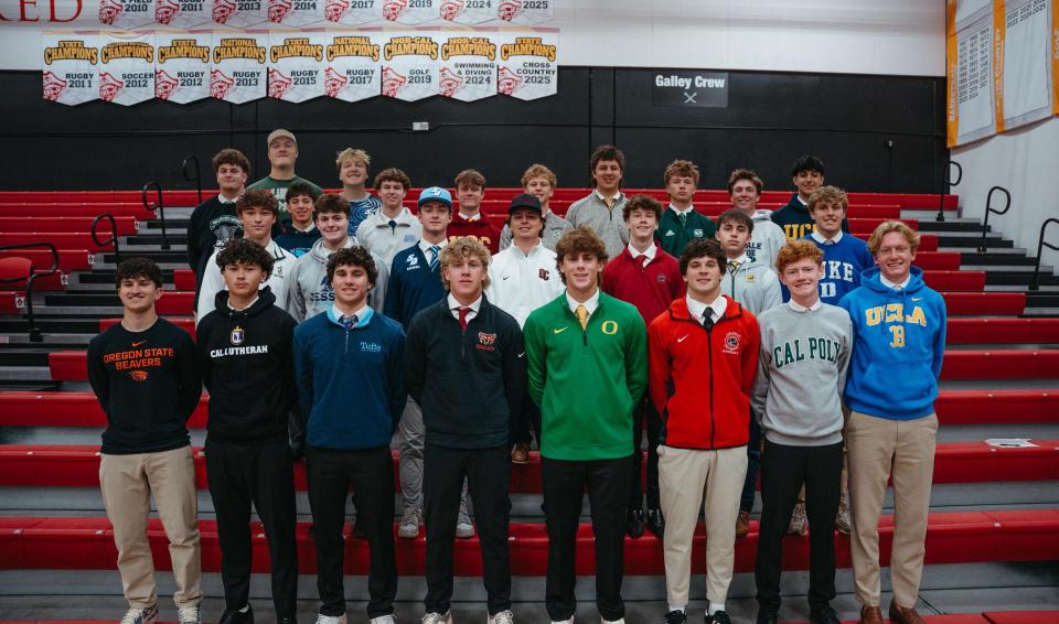 Group of seniors in college sweatshirts lined up in gym bleachers