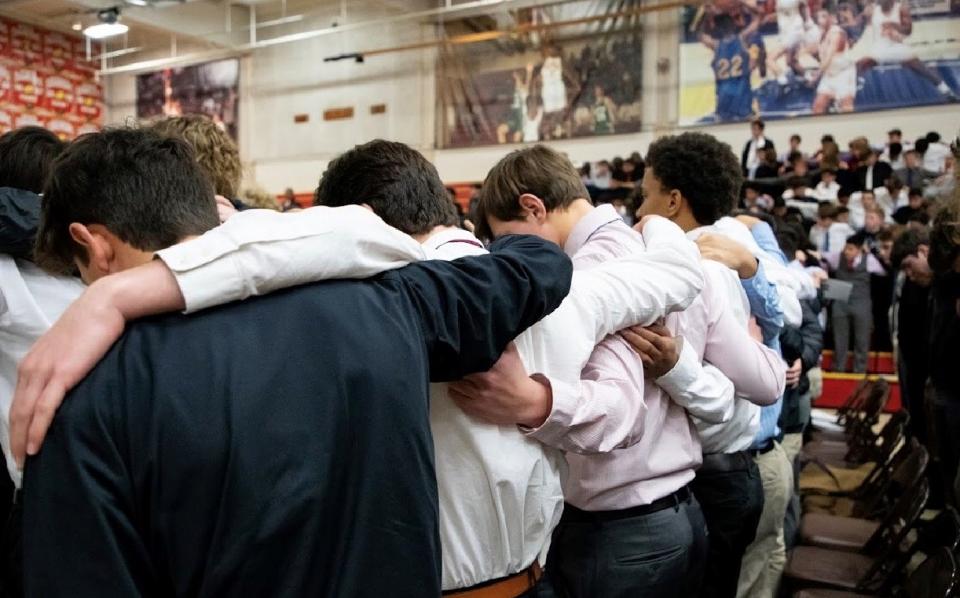 boys at Mass with hands over shoulders praying