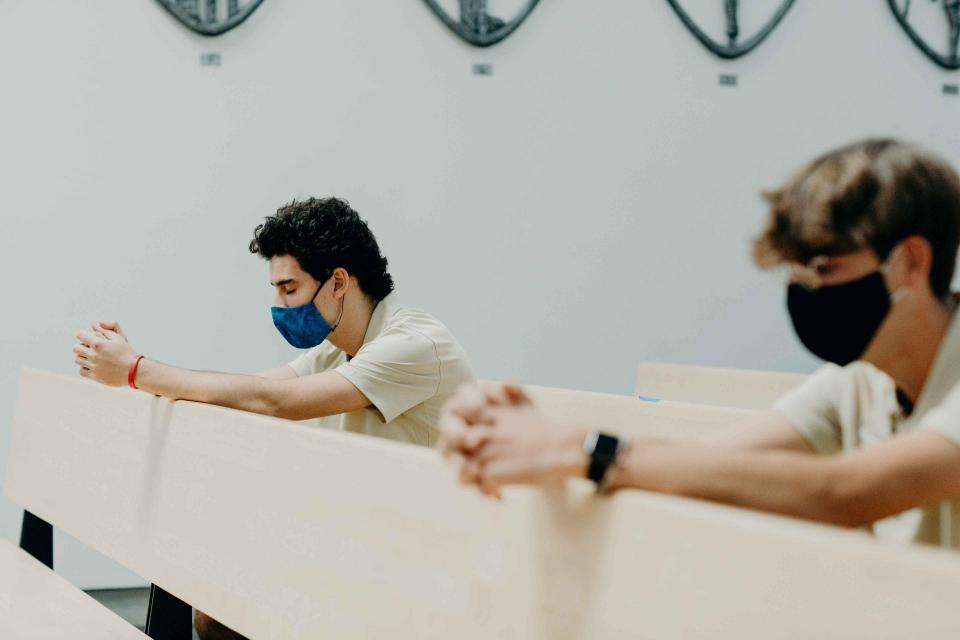 Two students kneeling in prayer in the chapel.