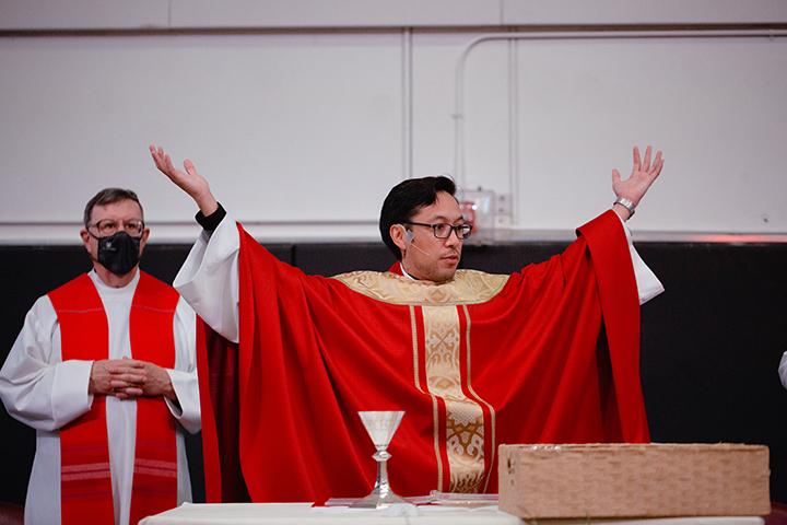 Image of Fr. Perry with arms outstretched at Mass last year