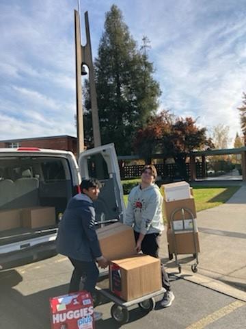 Students load boxes into the back of a school van