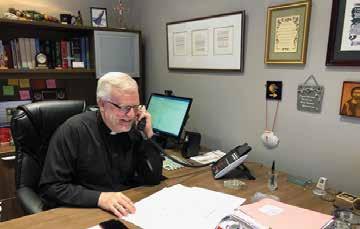 Image of Rev. McGarry, SJ on phone at desk in office