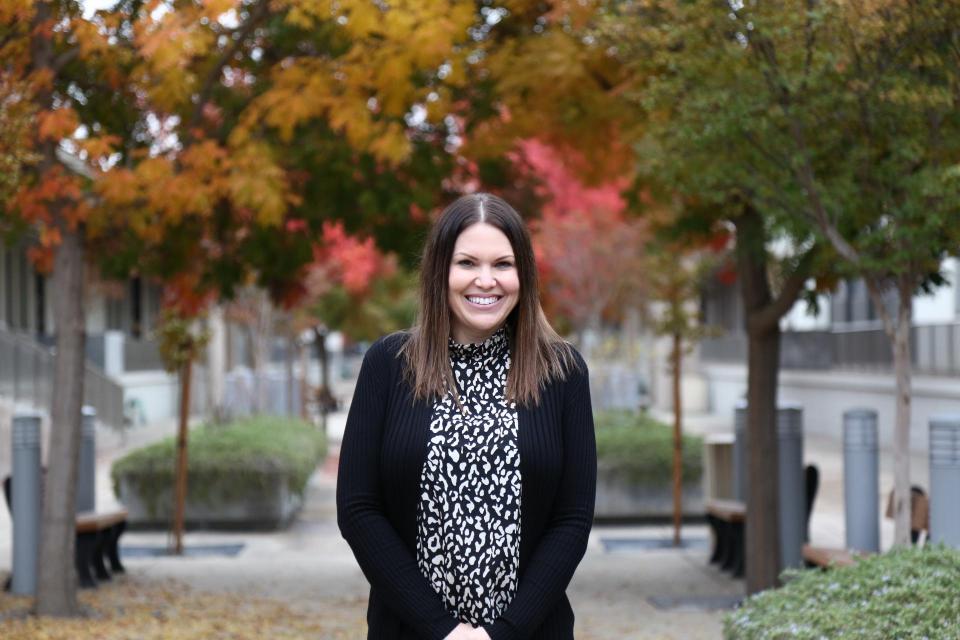 photo of smiling Misty standing on a street with trees in background
