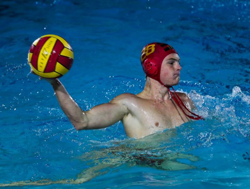 Water polo player in pool with ball in one hand.