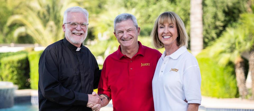 President Rev. John P. McGarry shaking hands with 1981 alumnus Tim Jeffries, his wife Mary Frances stands next to Tim