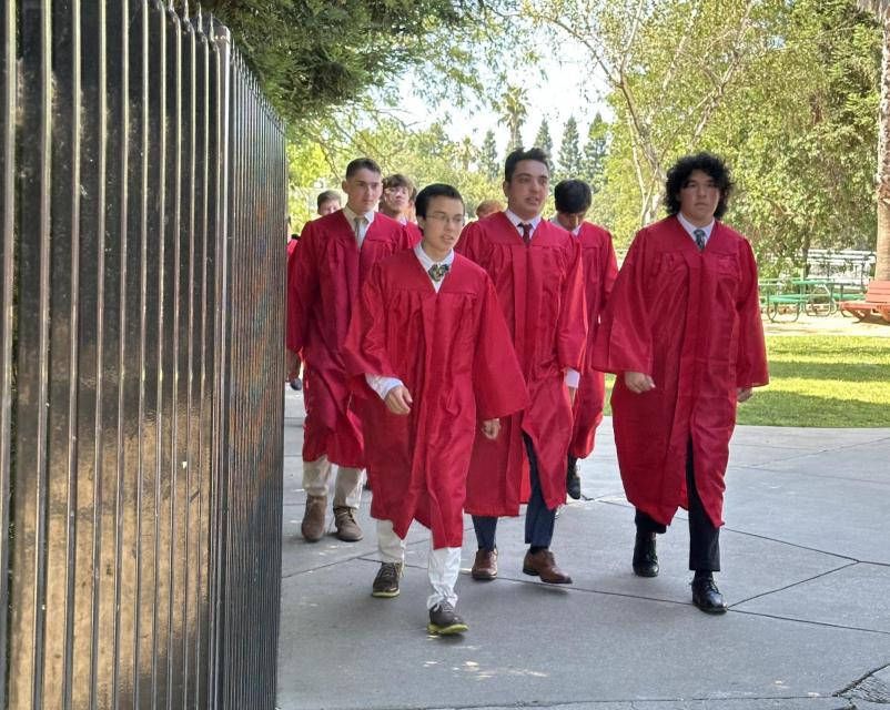 Group of students walking up from stadium in graduation robes