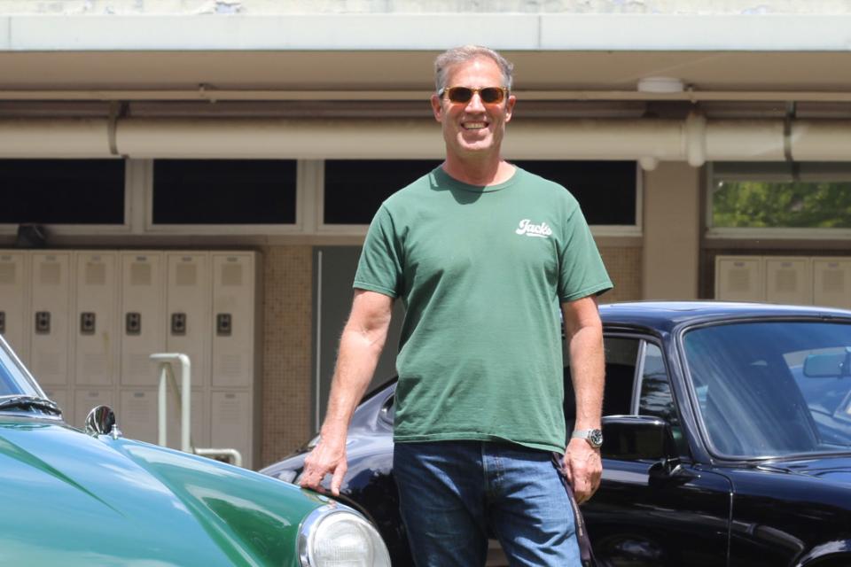 Rose standing between two classic cars in the senior quad