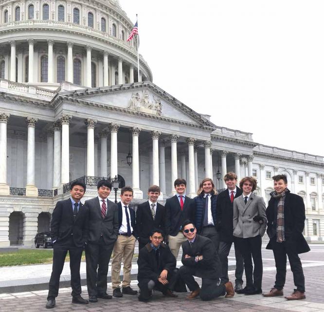 Student in winter coats pose as a group in front of the capital