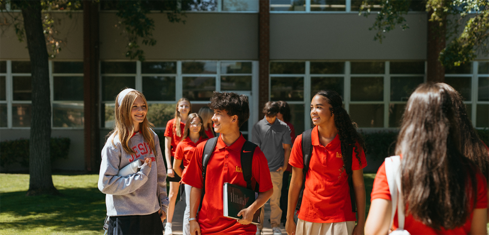 Image of boys and girls with backpacks  in Jesuit apparel talking and walking on campus