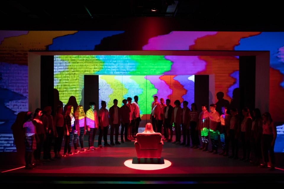 Dramatic stage with low lights and one chair under spotlight.