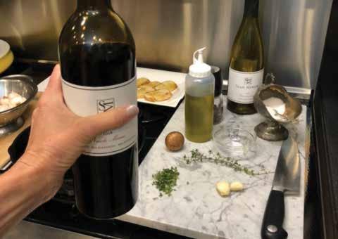Hand holding bottle of wine at home near food prep counter