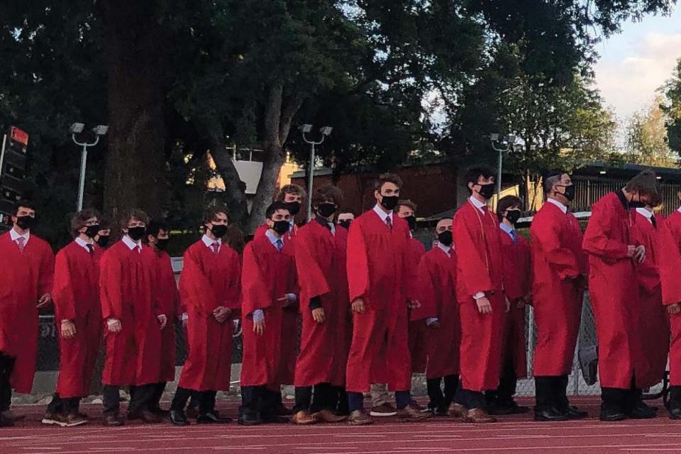 Rev. McGarry, SJ walks along side a line of graduates preparing for procession