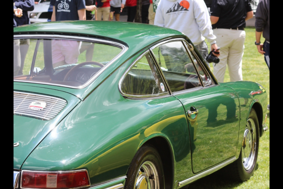 image of back of a vintage green Porsche with students milling around it on a sunny day