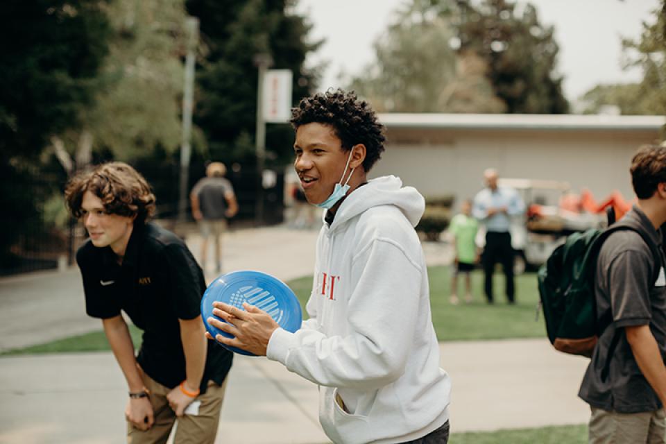 Image of students playing frisbee outside in quad