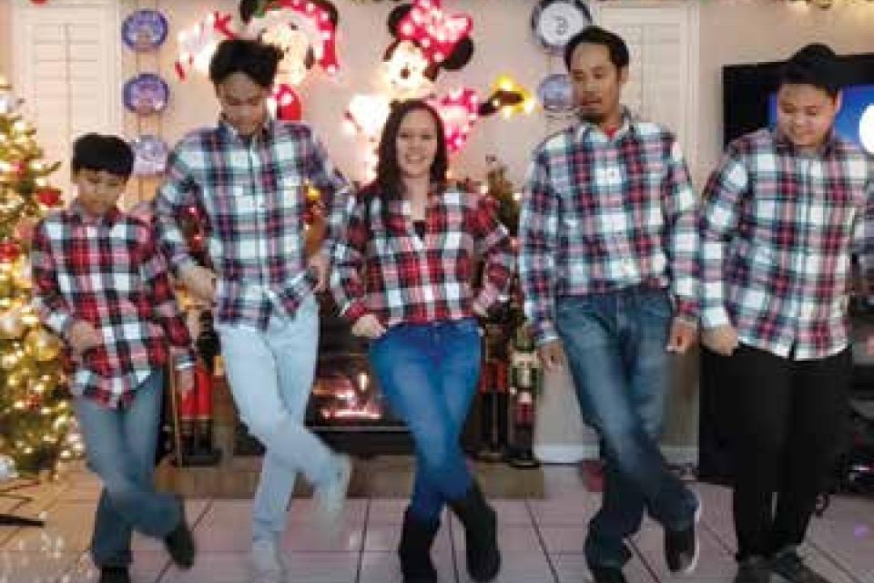 Family doing a line dance, wearing matching flannel.
