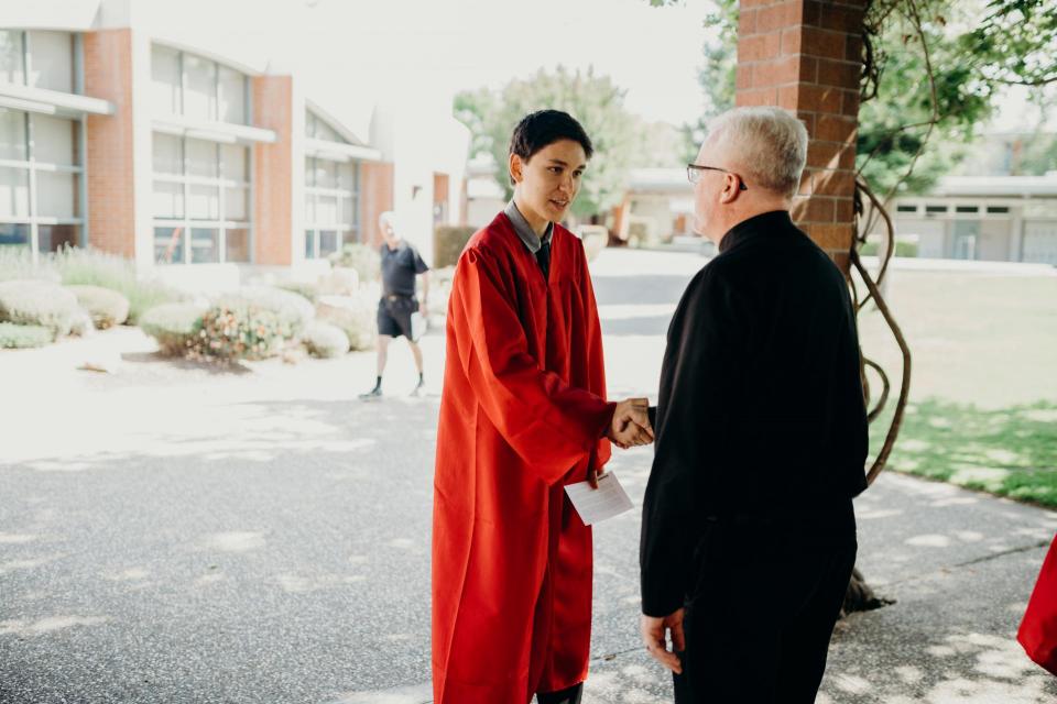 Fr. McGarry greets student at graduation rehearsal.