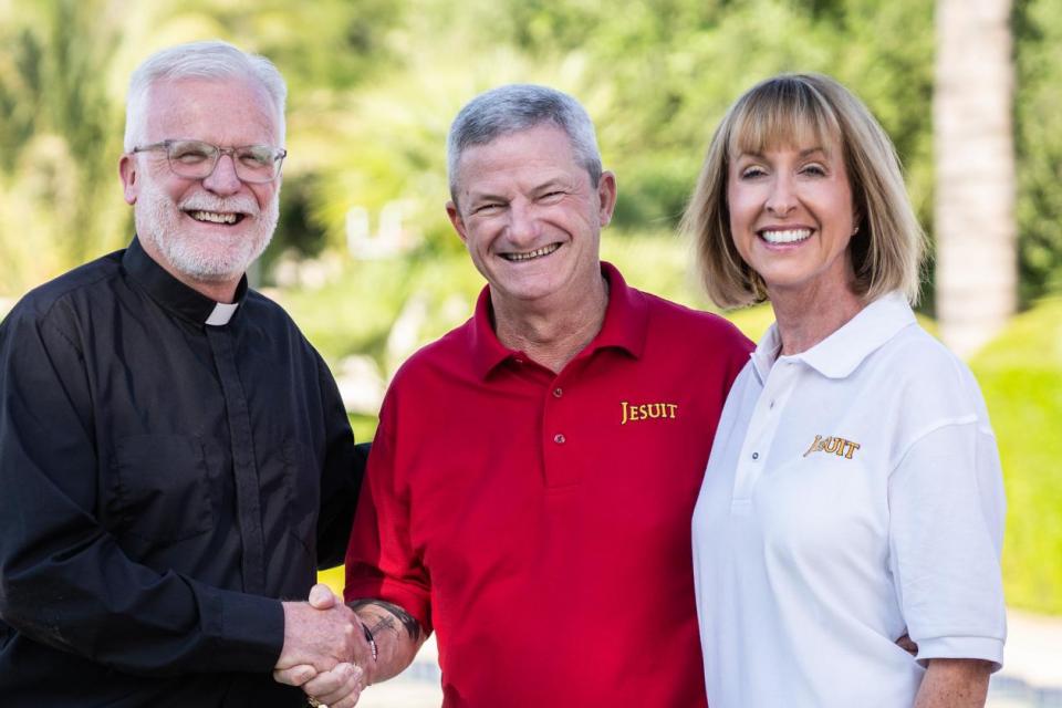 President Rev. John P. McGarry shaking hands with 1981 alumnus Tim Jeffries, his wife Mary Frances stands next to Tim