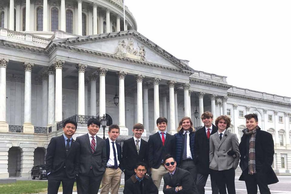 Student in winter coats pose as a group in front of the capital