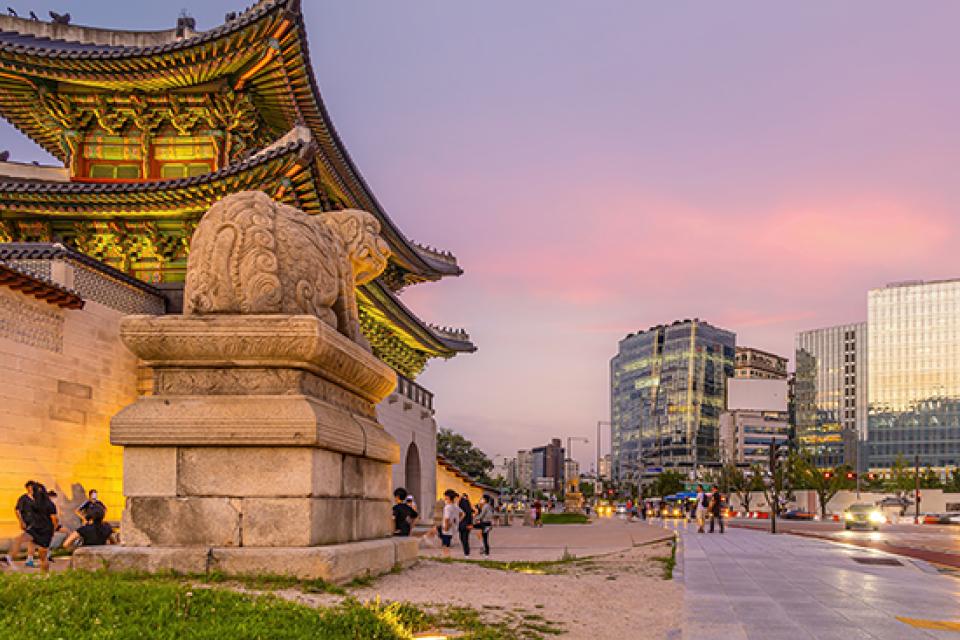 Gyeongbokgung Palace with city in background against pink and purple sky
