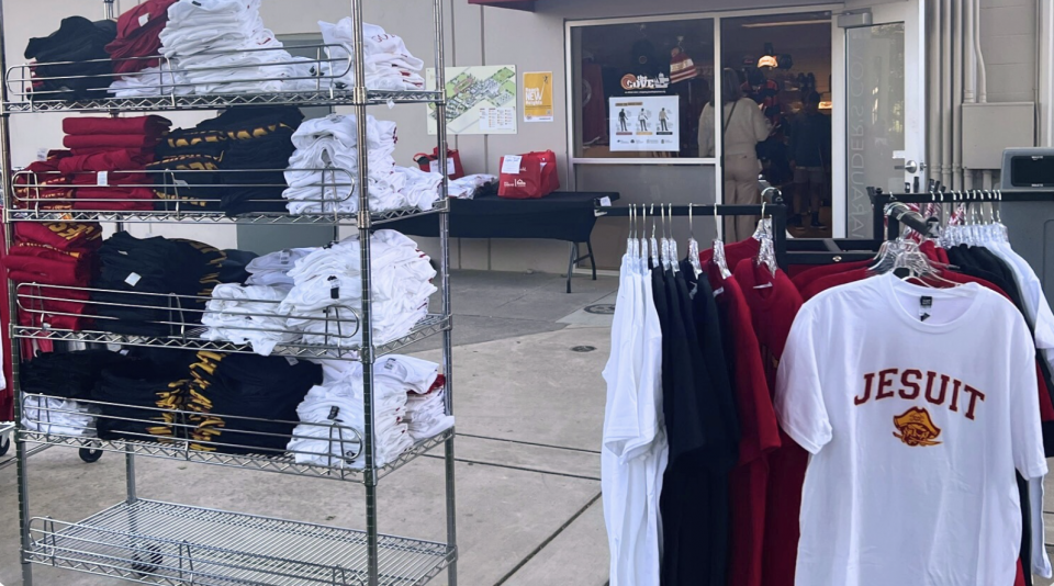 image of shirts, hats and sweatshirts on racks and shirts hanging on hangars outside the store