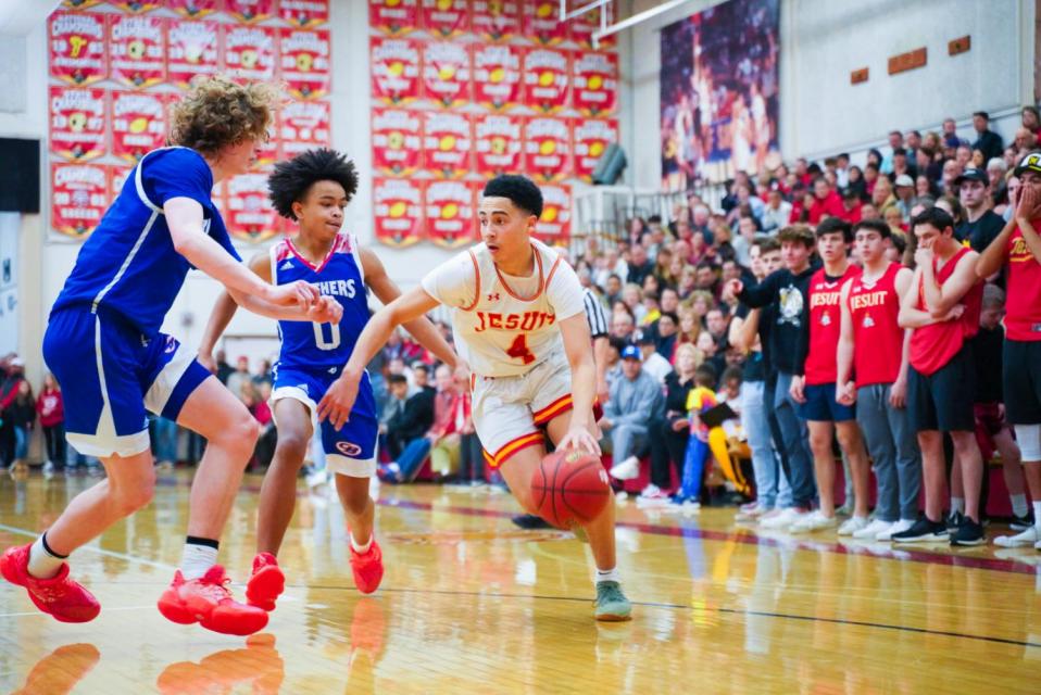 Jesuit player #4 dribbles around two CB players during game.