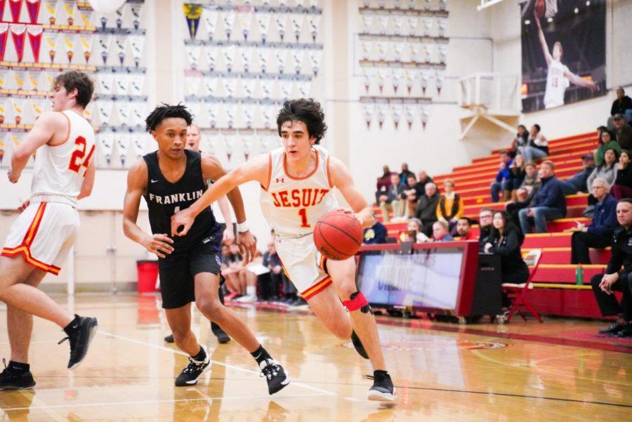 Jesuit guard Isa Silva '21 dribbles around defender against Franklin High School