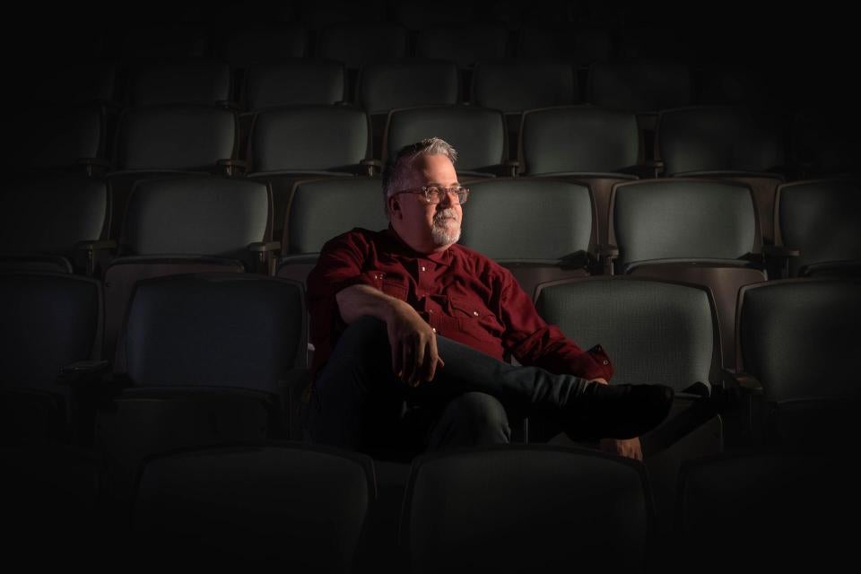 Ed Trafton sitting in an empty theater with dramatic lighting