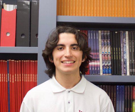 James standing in front of past student publications