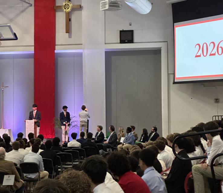 View of stage where student leaders adjust ribbons on class candles as colors are passed.