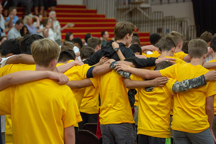 Image of the backs of a crowd of freshmen with arms linked in the gym