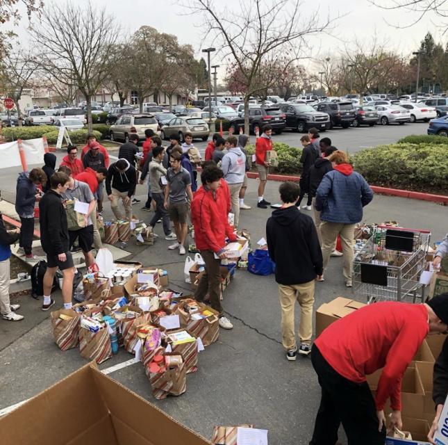 Full parking lot with students unloading cars and baskets full of canned goods