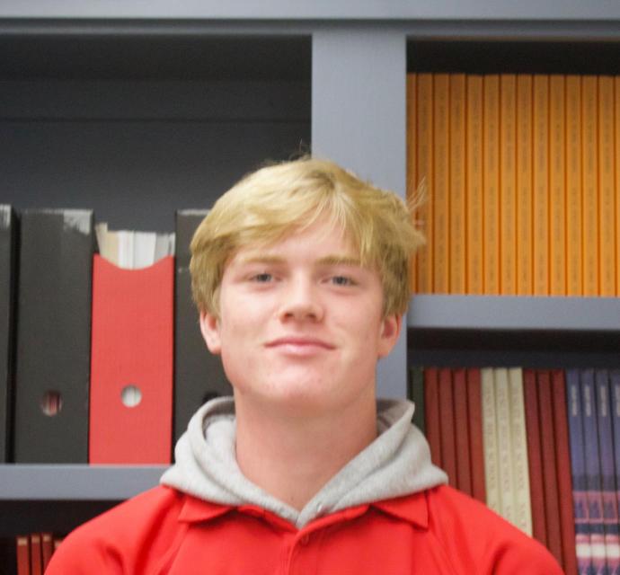 Kai standing in front of past student publications