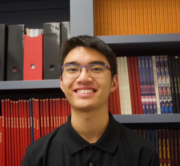 Matt standing in front of past student publications