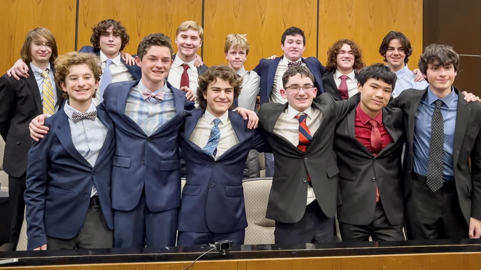 group of students smiling in suit and tie in a court room setting 