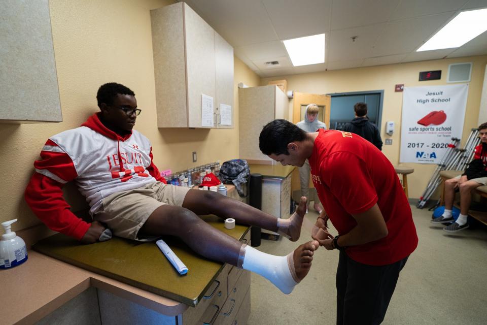 Athlete getting an ankle wrapped by trainer in an office.
